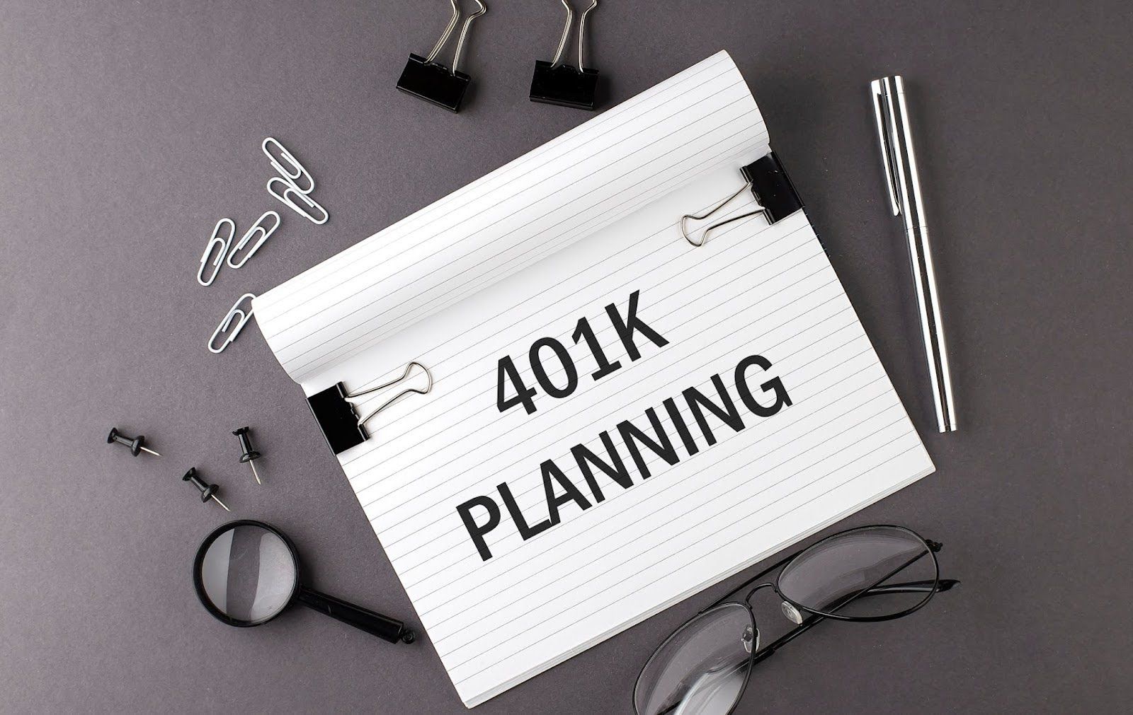Notepad printed with "401K PLANNING," against a gray backdrop