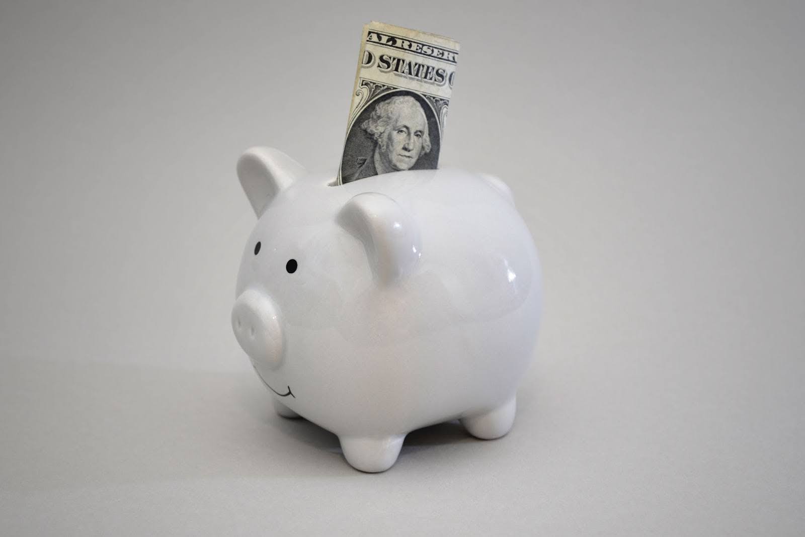 White ceramic piggy bank with dollar bill sticking out