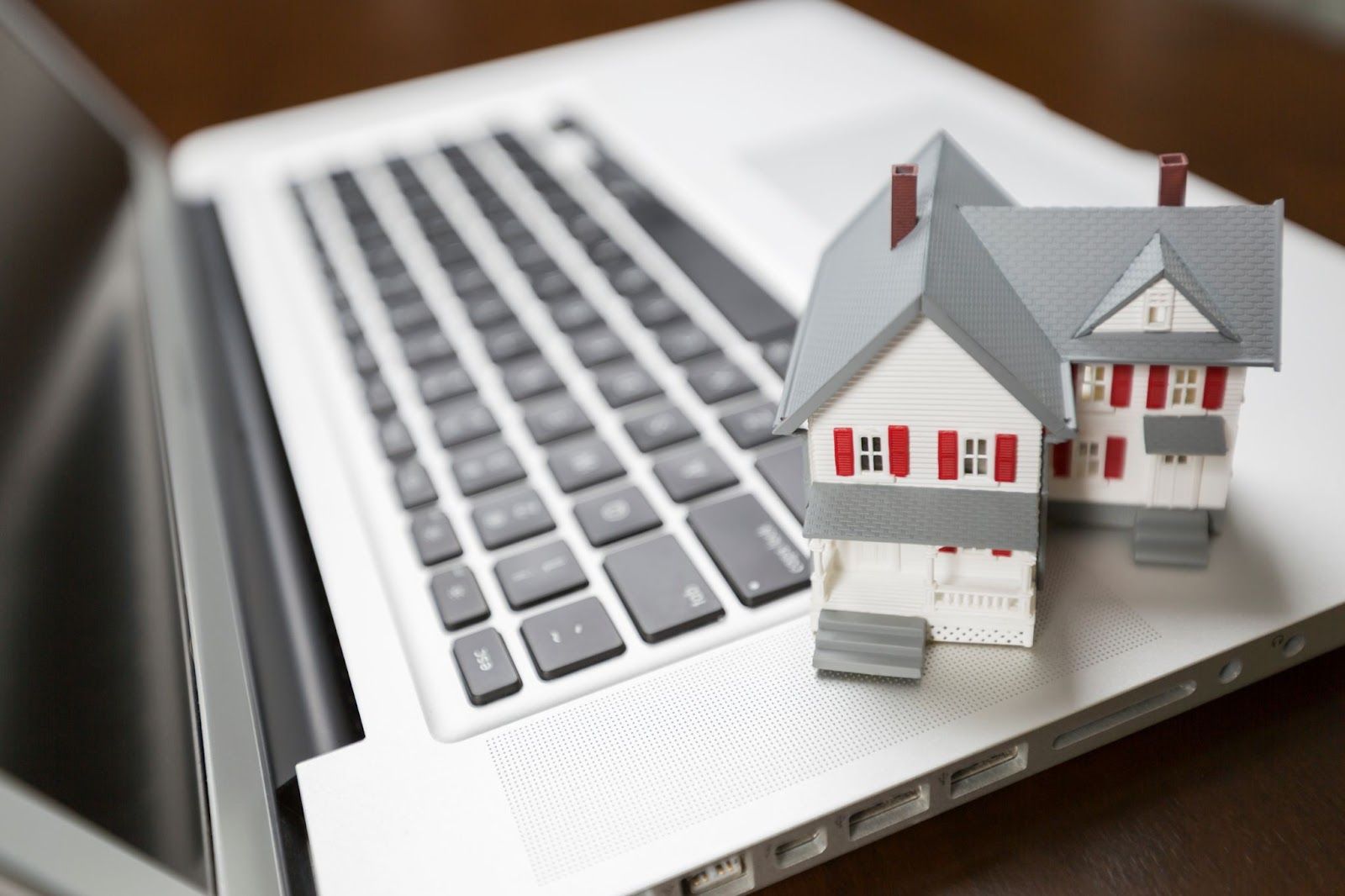 Model gray house balances on open laptop