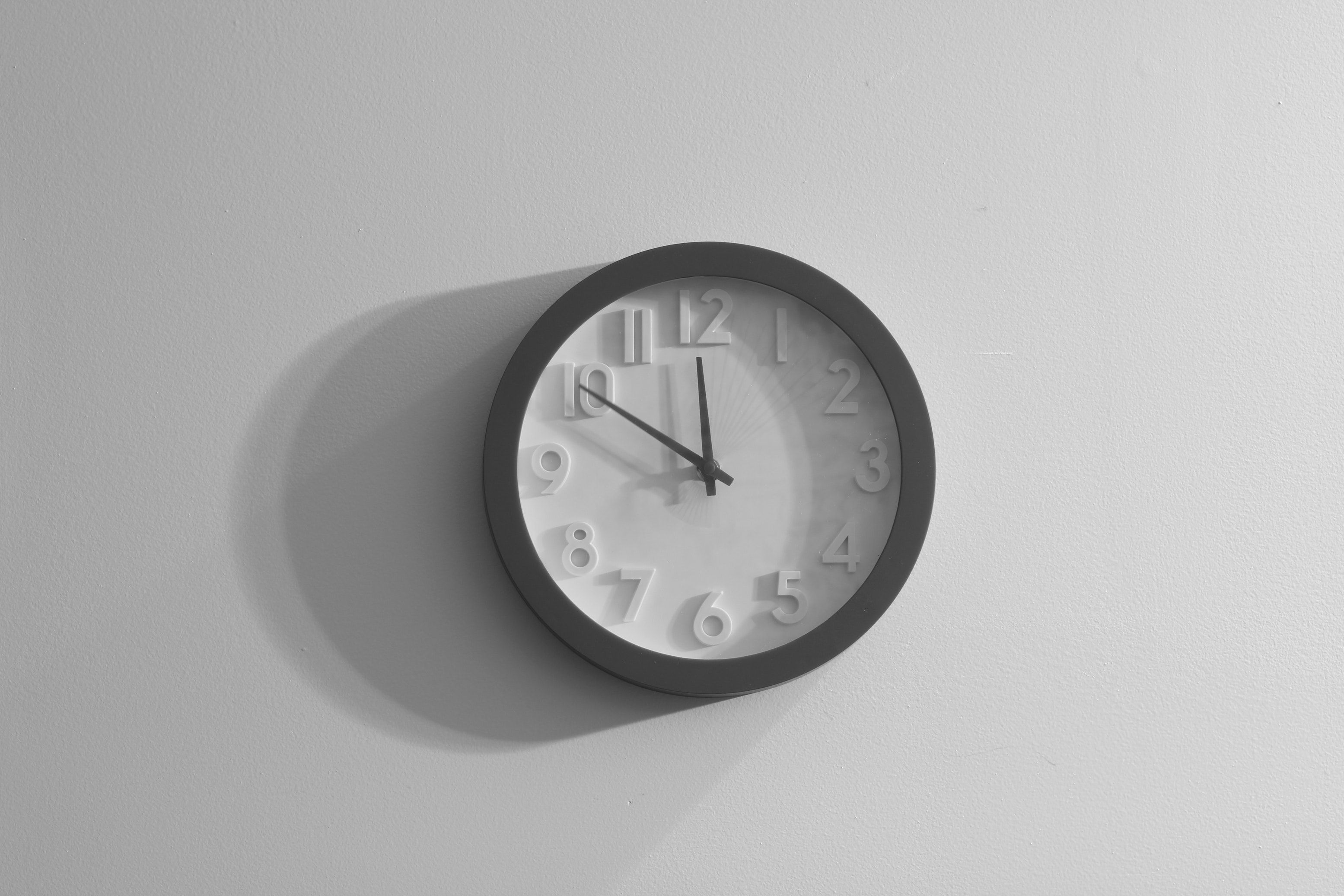 White-faced wall clock with a gray border hangs on a white wall