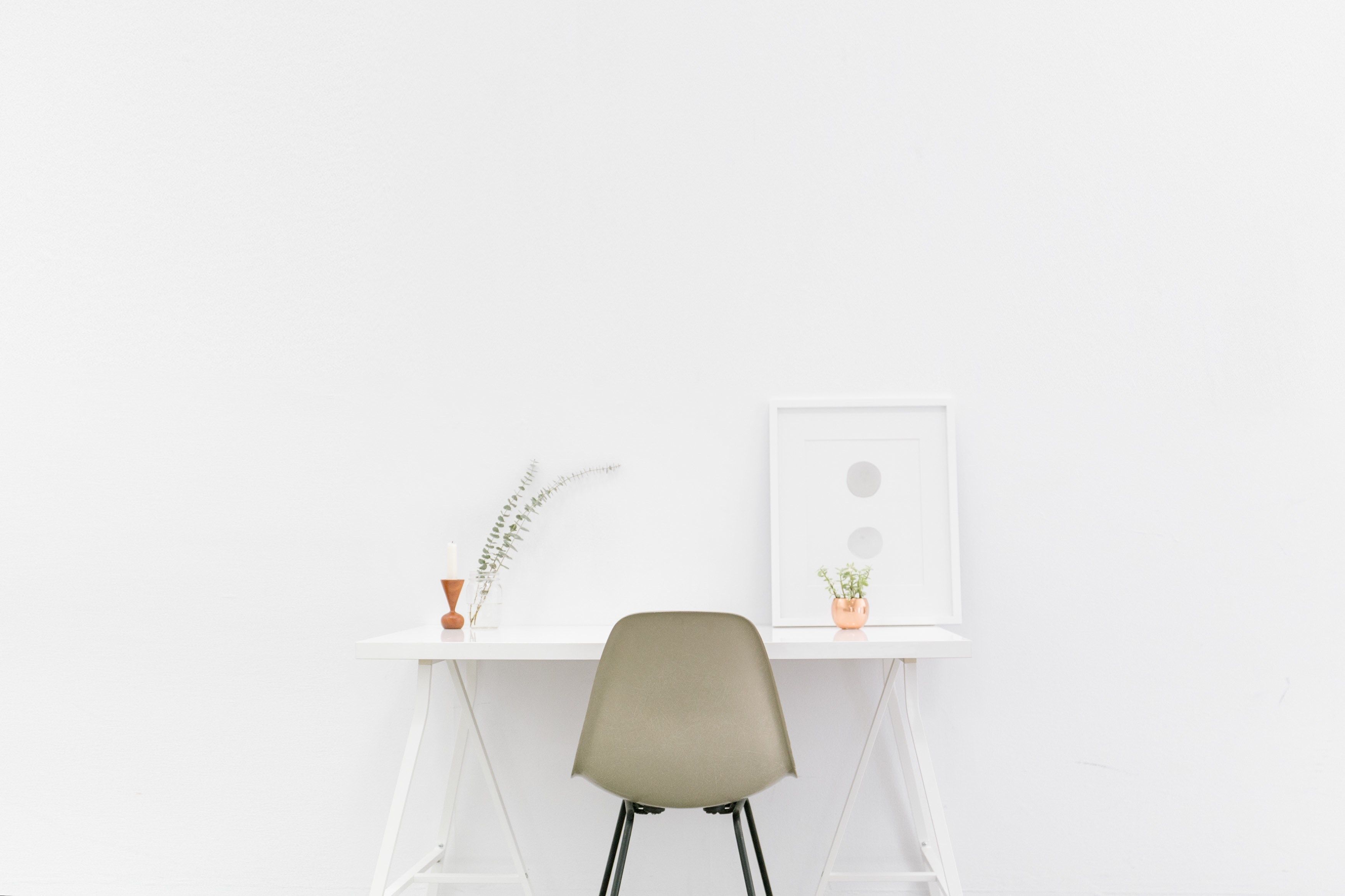 Minimal white desk with beige chair in a white room