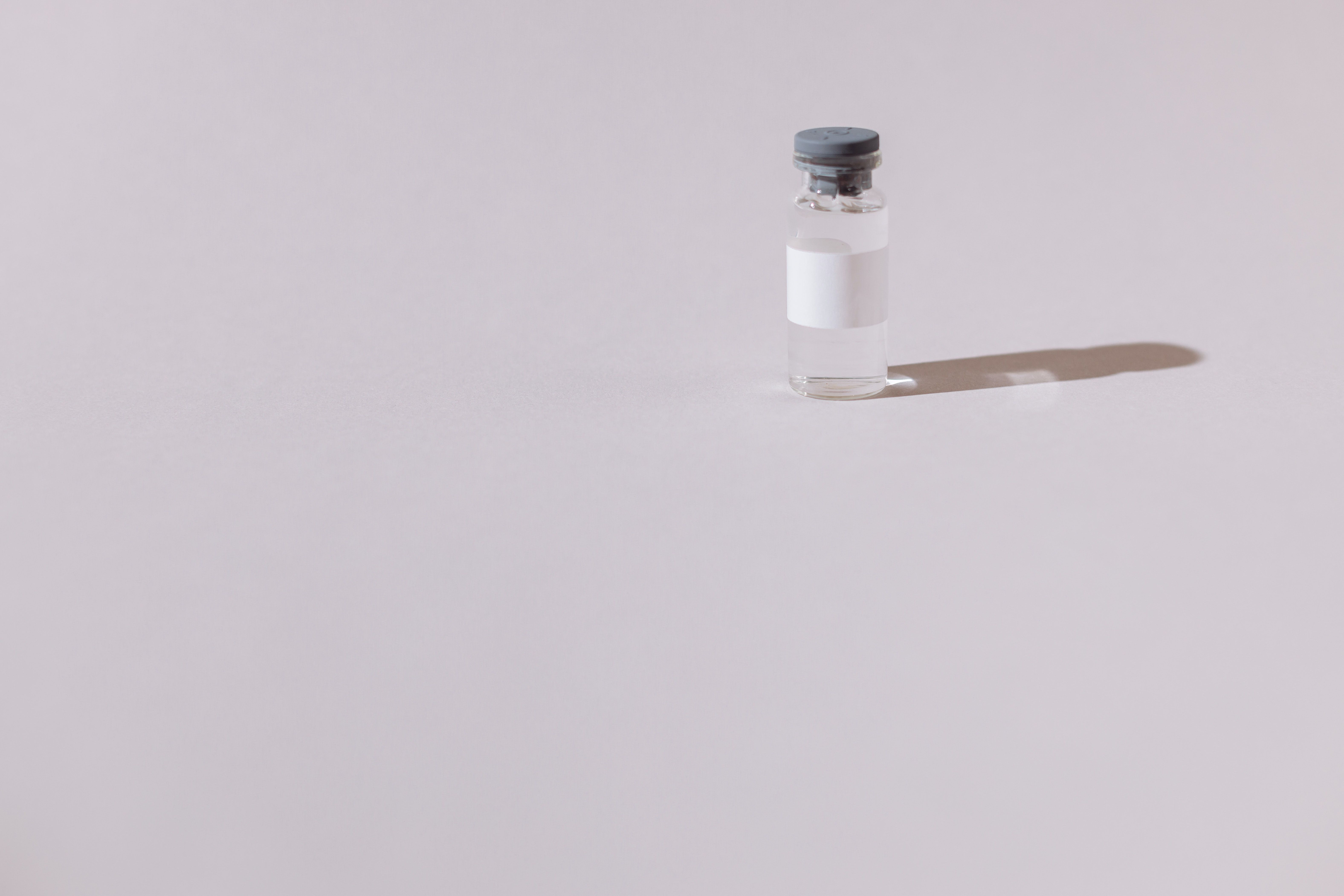 Glass vial with shadow against a gray background